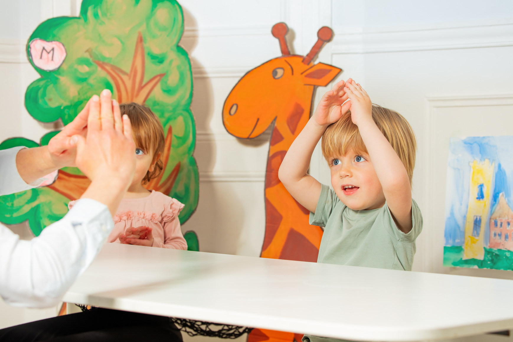 Two kids with teacher therapist play finger development game