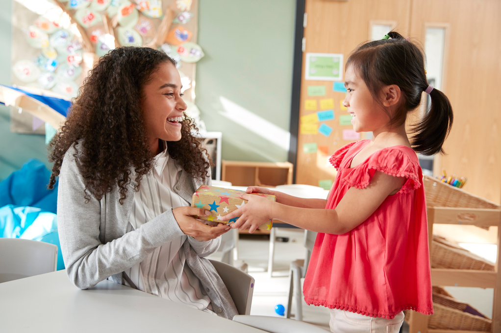 Kindergarten Schoolgirl Giving a Gift to Her Female Teacher in a